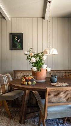 a wooden table with two chairs and a potted plant sitting on top of it