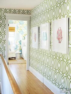 the hallway is decorated with green wallpaper and pictures on the wall, along with wooden banisters