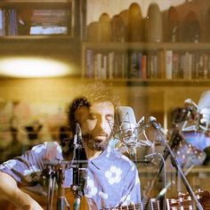 a man sitting in front of a microphone while playing an acoustic guitar and singing into a microphone