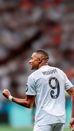 a male soccer player in a white uniform is holding his hand out to the side