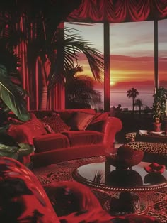 a living room filled with red couches next to a large window overlooking the ocean