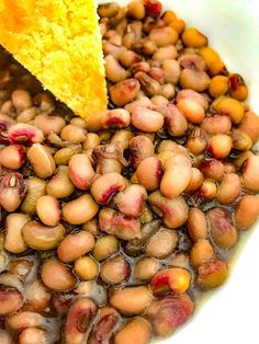 beans and corn on a white plate with a piece of cornbread in the middle