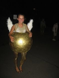 a woman dressed as an angel carrying a large golden ball