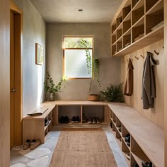 a wooden bench sitting under a window next to a shelf filled with shoes and plants