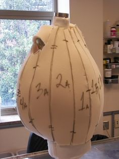 a large white vase sitting on top of a table next to a window with writing on it