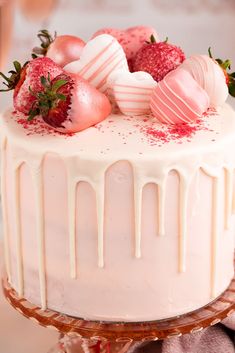 a white cake with strawberries on top and icing drizzled over it