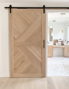 an open wooden door in the middle of a room with white walls and wood floors