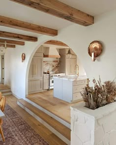 a kitchen with an archway leading to the living room and dining area is shown in this image