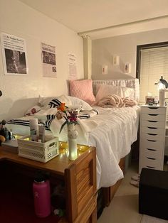 a bed with white sheets and pillows in a bedroom next to a dresser filled with personal items