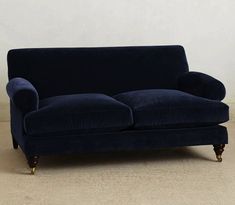 a blue couch sitting on top of a hard wood floor next to a white wall