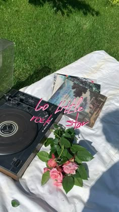 a record player sitting on top of a table next to a vase with pink flowers