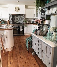 a kitchen filled with lots of white cabinets and counter top next to a wooden floor