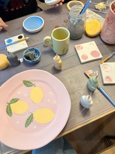 a plate with lemons painted on it sitting on a table next to other plates