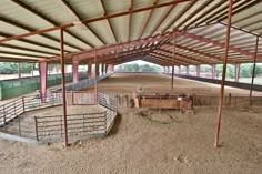 the inside of a building with several stalls and horses in it's pen area