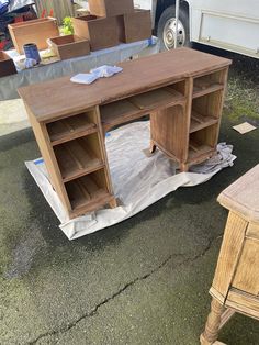 a wooden desk sitting on top of a tarp next to a white truck in a parking lot