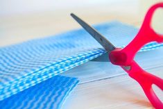 a pair of red scissors sitting on top of blue fabric