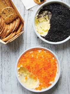 two bowls filled with food next to crackers