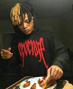 a young man with dreadlocks eating pizza