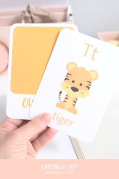 a person holding two cards with the words tiger and tiger on them, in front of a pink background