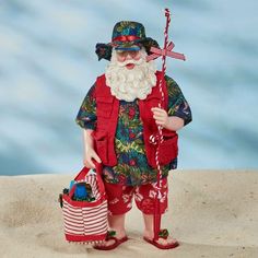 a santa clause figurine holding a red bag and wearing sunglasses, standing in the sand