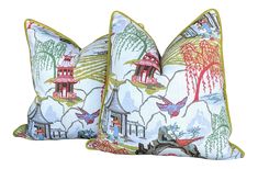 two decorative pillows with birds and pagodas on them, one in blue and the other in green