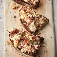 two pieces of bread with meat and cheese on it sitting on a cutting board next to some parmesan cheese