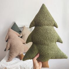 a hand holding three pillows shaped like trees