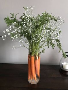 a vase filled with carrots and baby's breath on top of a wooden table