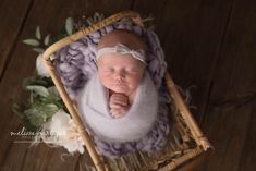 a newborn baby is laying in a basket with flowers on the floor and wearing a white headband