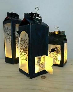 three lanterns with spider webs on them are sitting on a table next to each other