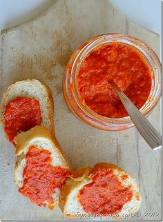 a piece of bread with sauce on it next to a jar of tomato sauce and a spoon