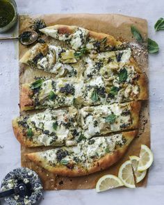 a pizza with cheese, spinach and other toppings on a wooden cutting board