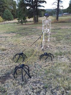 a skeleton is tied up to two black spider legs in the middle of a field