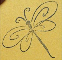 a drawing of a dragonfly is shown on a piece of yellow paper with black ink