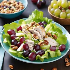 a salad with grapes, chicken and nuts on it