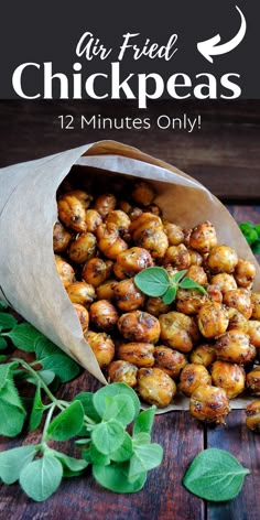 a bag full of chick peas sitting on top of a wooden table next to green leaves