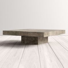 a concrete table sitting on top of a wooden floor next to a white wall in an empty room