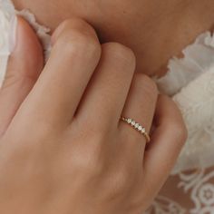 a woman wearing a gold ring with three diamonds on the band and a white lace dress