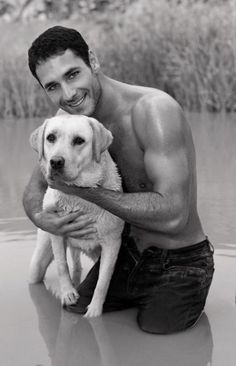 a man holding a dog in his arms while sitting on top of a body of water