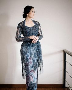 a woman in a blue dress standing on a wooden floor next to a white wall