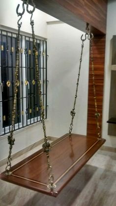 a wooden swing with metal chains hanging from it's sides in an empty room