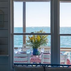 a living room filled with furniture and a large window overlooking the ocean on a sunny day