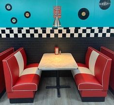 two red booths with black and white checkers on the walls, one booth is empty