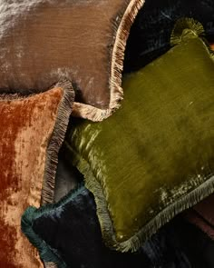 three different colored velvet pillows stacked on top of each other with fringe trim around the edges