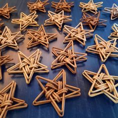 many small wooden stars are arranged on a blue table top and one is made out of wood sticks