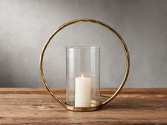 a candle sits in a glass holder on a wooden table