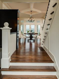 a staircase leading to a dining room and living room with chandelier hanging from the ceiling