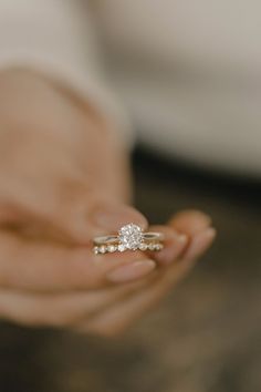 a close up of a person holding a ring in their hand with the diamond on it