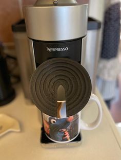 a coffee maker with a roll of black cloth on top of it next to an espresso machine