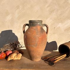 an old vase sitting on top of a wooden table next to bread and other items